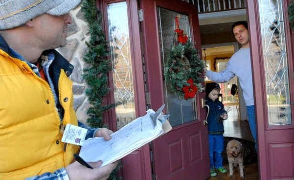 John Fries had a few questions for Chuck Rupertus, at the door with son Alex, 5, and their pooch. Rupertus had a question of his own: "Why do we even have this guy? I pay $14,000 a year in property taxes, and they're nickel-and-diming me about my dog."