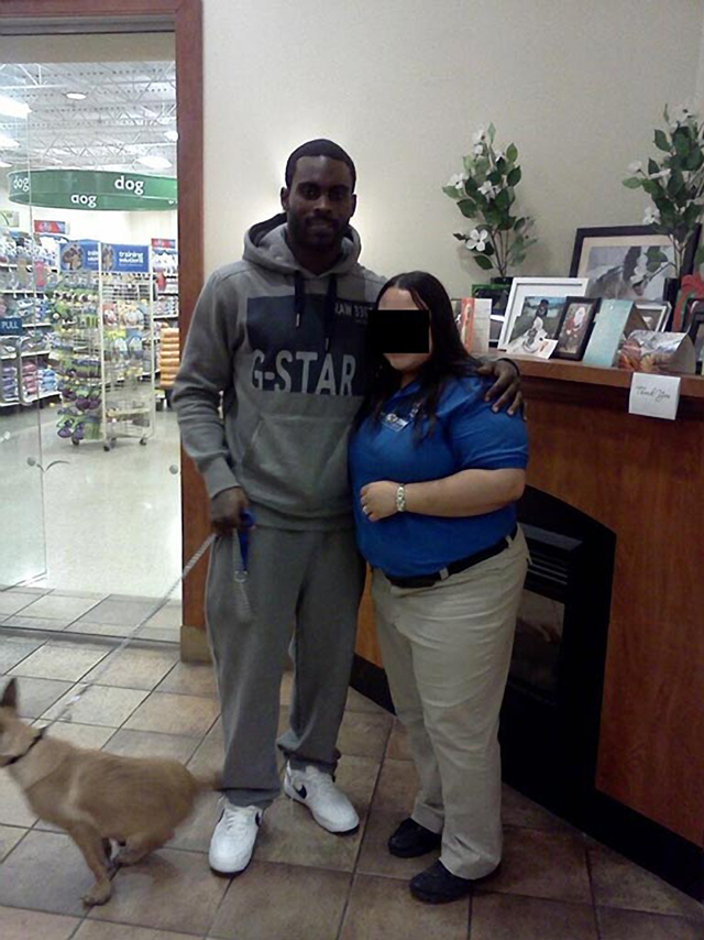Michael Vick posing with a PetSmart employee and his puppy, Angel.